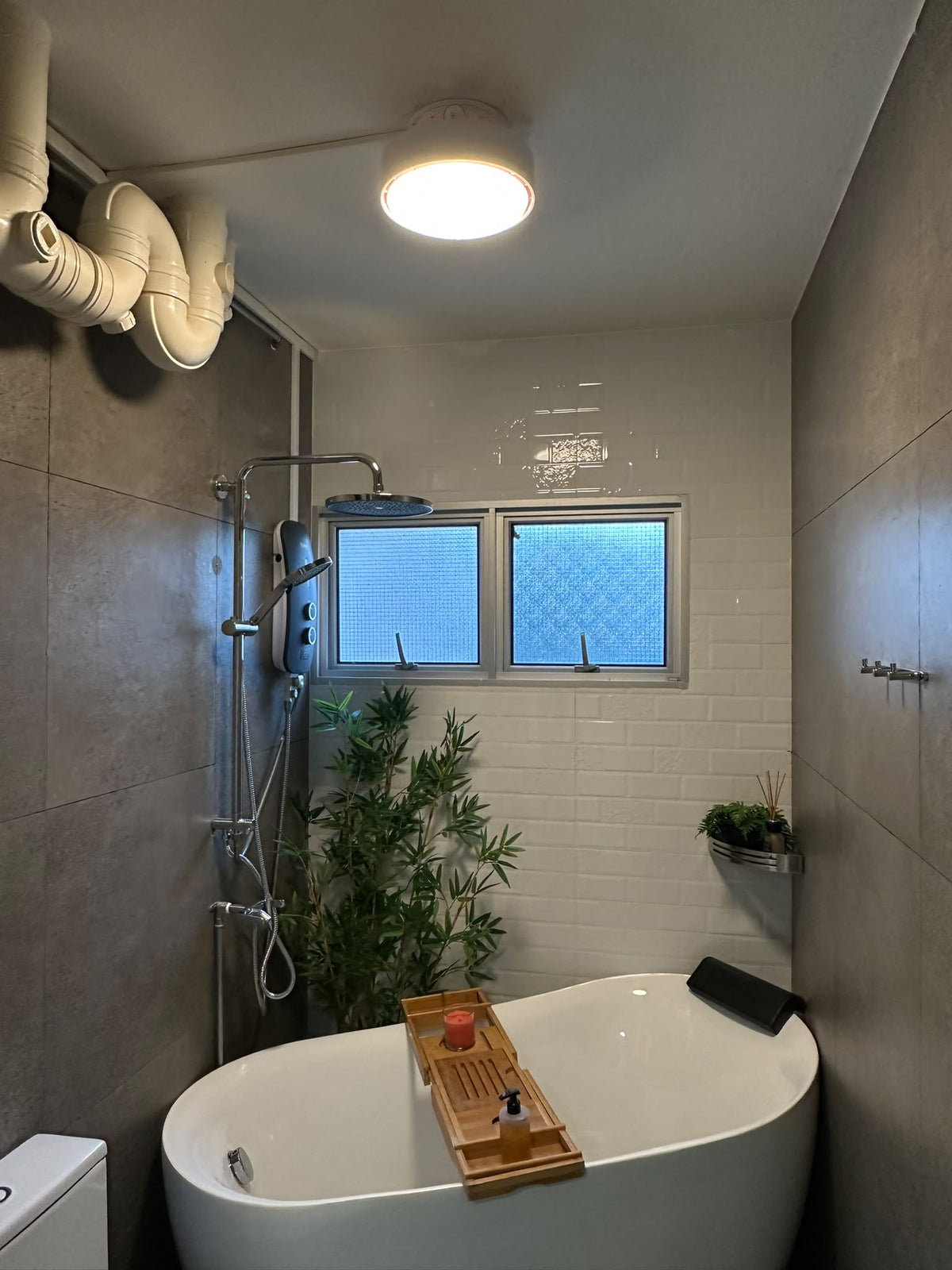 ALANTZ Aura-Flow Compact ceiling fan with its LED light on above a bathroom with a freestanding bathtub